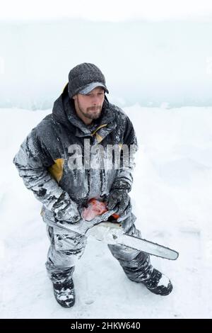 Worker with a chainsaw in hand at the assembly site Stock Photo