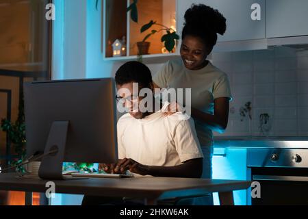 Young web developer working from home, code app or programming with support of caring black wife Stock Photo