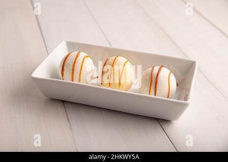Ice cream Mochis with caramel (cajeta). Traditional Japanese dessert made from rice flour. Close up on white wooden surface. Stock Photo