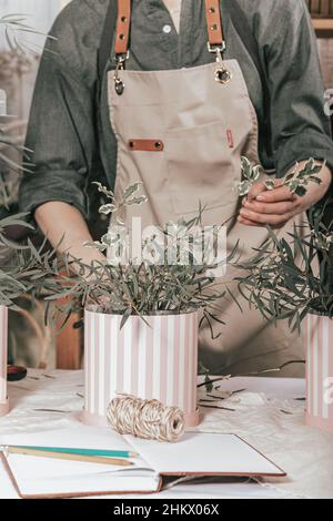 Florist make gift bouquets in hat boxes. Graceful female hands make a  beautiful bouquet. Florist workplace. Small business concept. Front view.  Flowers and accessories - a Royalty Free Stock Photo from Photocase
