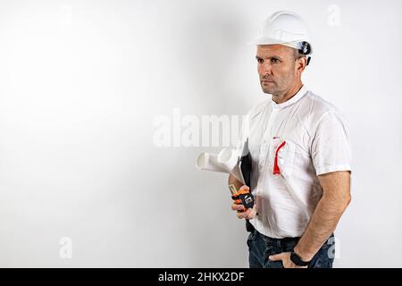 Male engineer in a white hard helmet. A middle-aged man in a white shirt, with blueprints and a tablet computer. Isolated portrait on a white backgrou Stock Photo