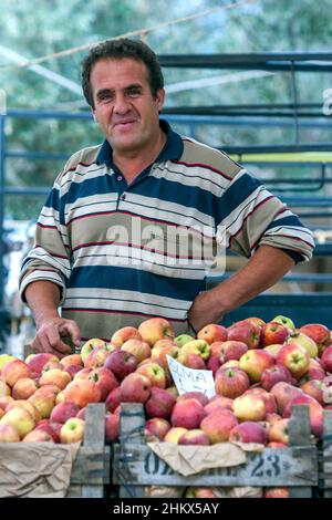 A Turkish greengrocer selling apples at the Kas Friday market. Kas is a village which sits on the Mediterranean Sea in Stock Photo