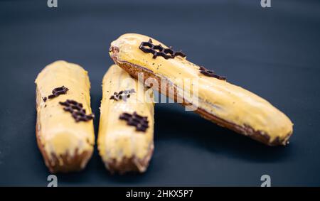 Close-up of eclairs in yellow glaze on a black background. Stock Photo