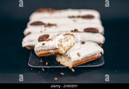 Close-up of eclairs in white glaze with pecans. Stock Photo