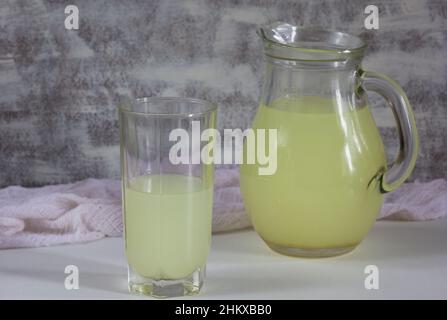 Jar and glass with liquid whey that remains after formation of curds on the white background Stock Photo