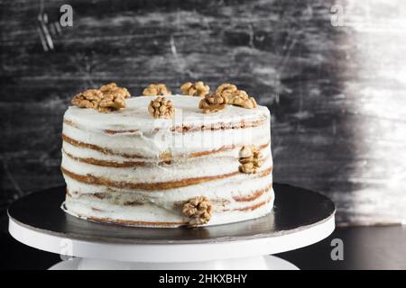 Honey cake with sour cream frosting decorated by walnuts on the black background Stock Photo