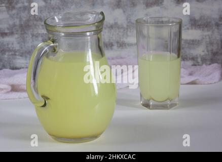 Jar and glass with liquid whey that remains after formation of curds on the white background Stock Photo