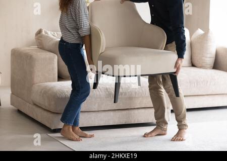 Couple carrying chair, placing furniture in new apartment cropped Stock Photo