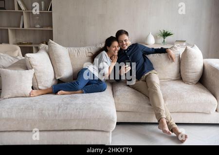 Happy woman and man hugging, using smartphone together Stock Photo
