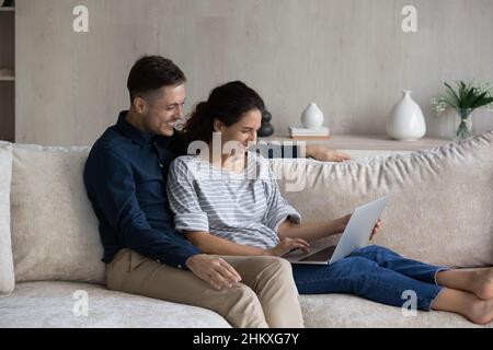 Happy loving couple using laptop, relaxing on couch together Stock Photo