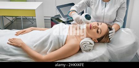 Removal of brown spots, freckles and rosacea on female face at cosmetology using machine with intense pulsed light IPL technology Stock Photo