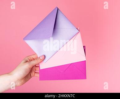 Valentines day concept. Hand holding envelopes with greeting cards, gift certificates, love confession on pink background. High quality photo. High quality photo Stock Photo