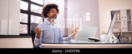 African American Male Meditation In Office Near Computer Stock Photo