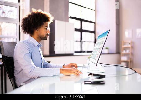 African American Man Looking At Agenda Using Calendar On Tablet Computer Stock Photo