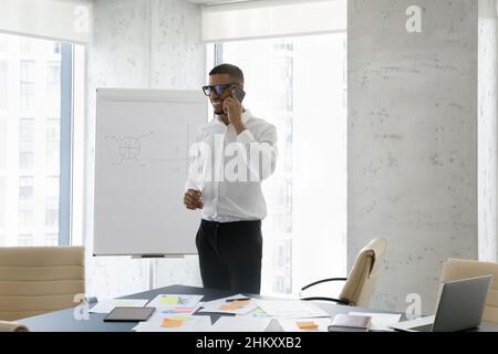 Happy friendly successful African businessman talking on mobile phone Stock Photo
