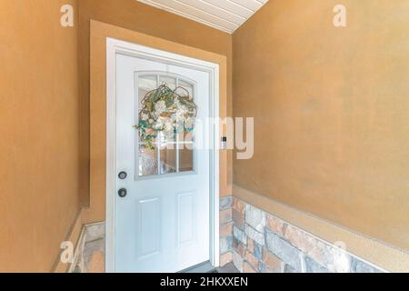 White front door with wreath over the glass panels and doorbell with camera Stock Photo
