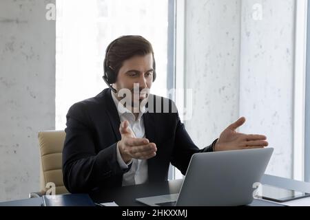 Serious business professional man in headphones with mic using laptop Stock Photo