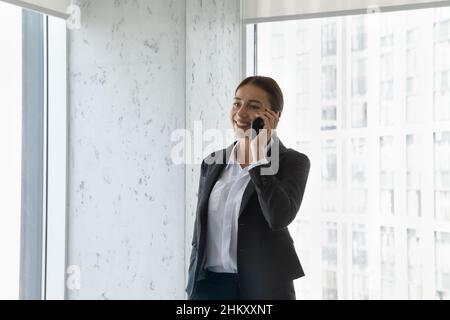Happy satisfied manager speaking on mobile phone in office hall Stock Photo