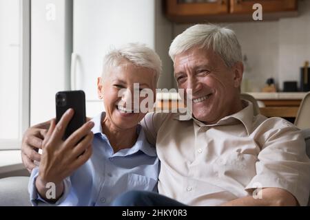 Happy joyful senior couple taking home selfie on mobile phone Stock Photo