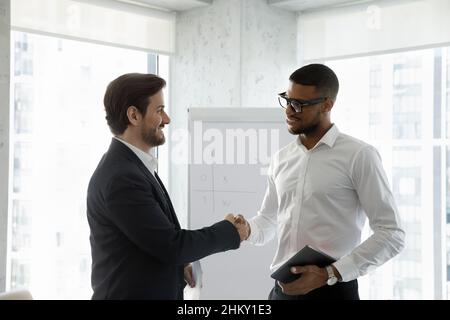 Two diverse smiling business men shaking hands in office boardroom Stock Photo