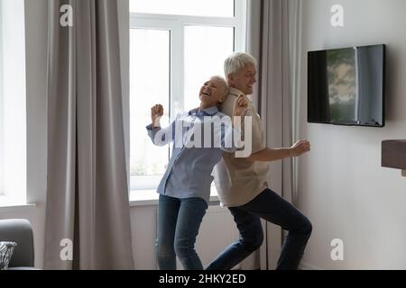 Happy mature couple dancing to music together in living room Stock Photo