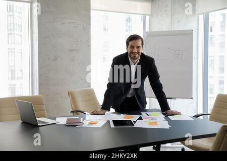 Happy successful business leader standing alone at table Stock Photo