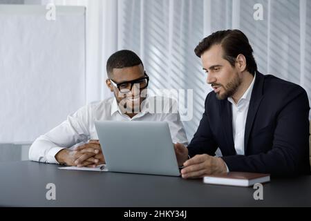 Diverse office employees in formalwear of using laptop computer together Stock Photo