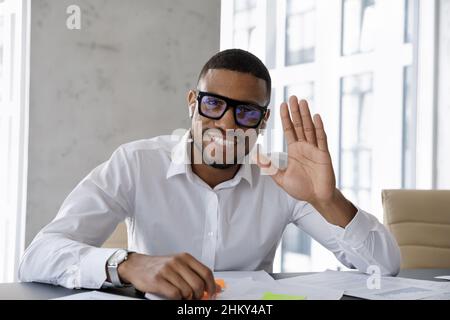 Happy millennial African business leader in glasses waving hand hello Stock Photo