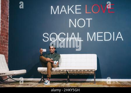 Creative businessman speaking on a video call in an office lobby. Confident young businessman communicating with his partners using a smartphone. Mode Stock Photo