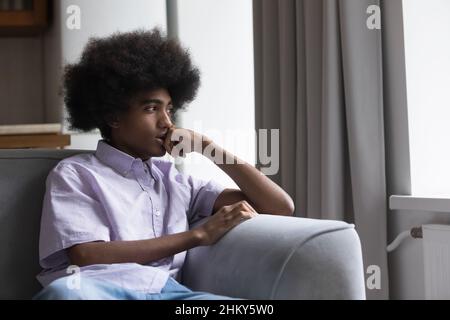 Thoughtful sad teen Black guy sitting on sofa Stock Photo