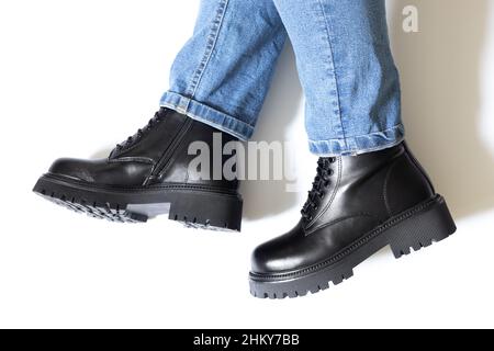 Closeup of female leather boots of black color with block heel, round toe and embossed hard sole on woman feet isolated on white background with Stock Photo