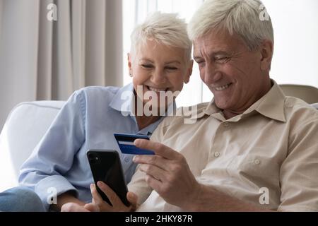 Happy mature couple of customers using smartphone for online shopping Stock Photo