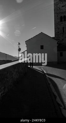 person walking towards the church with the sun in front Stock Photo