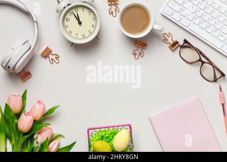 Desktop. Notepad keyboard coffee cup alarm clock on the table with easter decorations. Frame border flat lay copy space top view Stock Photo