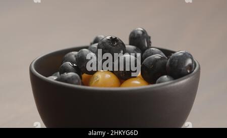 blueberries in black bowl with physalis closeup, wide photo Stock Photo