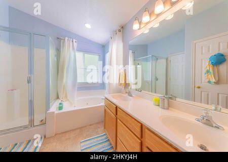 Bathroom with light blue walls and windows at the corner with curtains Stock Photo