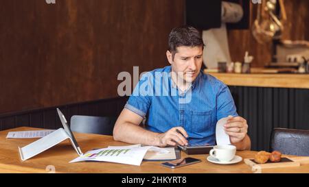 Mature new small business owner calculating online restaurant bill expenses and taxes Stock Photo