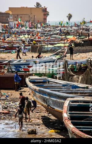 View of kids playing among colorful painted pirogues in the fisherman's wharf of Saint-Louis-du-Sénégal, Senegal Stock Photo