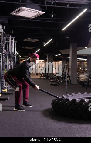 A man hits a sledgehammer wheel in fitness, the concept of a healthy lifestyle male sledgehammer active hit hammer, from gym muscular for athlete for Stock Photo