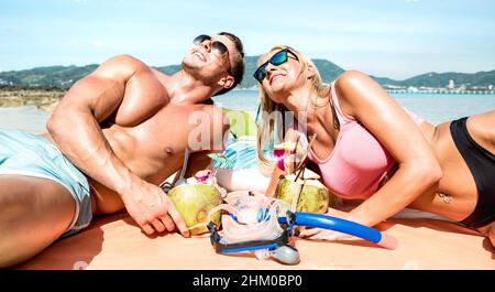 Young couple travelers drinking cocunut cocktail and having fun on tropical beach - Luxury life style concept with fashion influencers traveling aroun Stock Photo