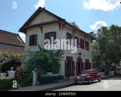 Laos, Luang Prabang - nice scene in the streets with a historic car in front of a tradioniol building with nice mirroring from the sun Stock Photo