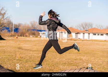 young female runner is jumping over wooden hurdles in countryside - concept of health and wellness Stock Photo