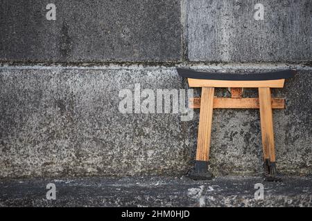 Small Shinto shrine torii gate up on a concrete wall Stock Photo