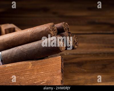 Cigars in a wooden box on a wooden table. Copy space. Stock Photo