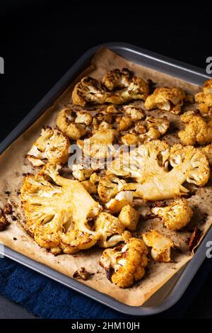 Food concept Roasted organic Cauliflower in baking tray on black slate stone background with copy space Stock Photo