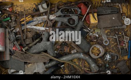 Old rusty tools are in the drawer. A dirty box with construction tools. Garbage of tools and bolts and nuts in the drawer. Rusty vintage tools. Vintag Stock Photo