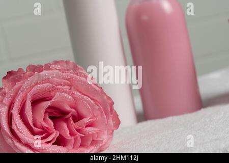 Pink rose on the background of cosmetic jars. Beauty, self-care. Flower close-up. Drops of water on the petals of a flower. Pink background, tendernes Stock Photo