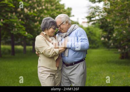 Portrait of happy loving married senior couple hugging in green city park Stock Photo