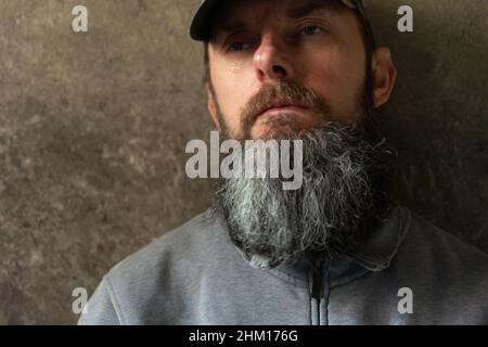 Bearded man in a baseball cap on the dark wall background Stock Photo