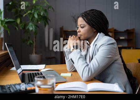 Serious businesswoman sit at office desk looking at laptop screen read email with important news Stock Photo